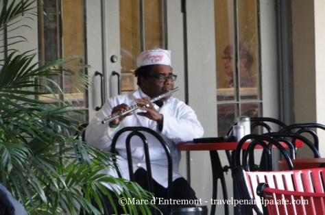 Staff member of Morning Call Coffee Stand playing the flute during break, City Park, New Orleans